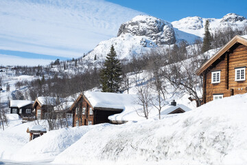 Cozy wooden cabin under snow in the mountains during winter. Ski center accommodation. 