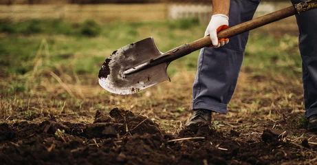 Fotobehang Chocoladebruin The gardener digs the garden with a shovel  © sushytska