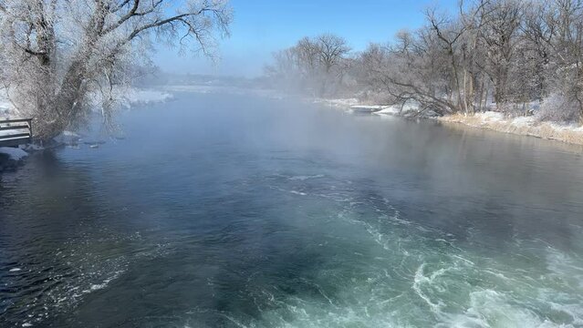 Bubbling river flows past snowy bank and frosty trees