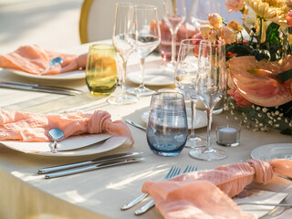 Beautiful outdoor wedding decoration in city. Candles and dried flowers and accessories with bouquets and glasses on table with linen tablecloth on newlywed table on green lawn