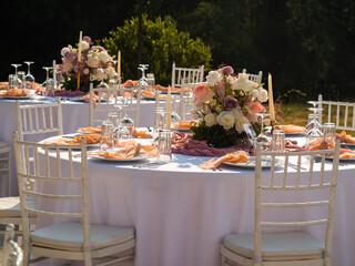 Wedding banquet concept. Chairs and round table for guests, served with cutler and, flowers and crockery and covered with a tablecloth