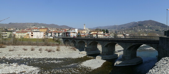 panorama of the village of Borgotaro with the arched bridge over the Taro river in the foreground and the hills in the background