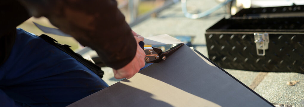 Banner mit Dach Bauklempner Handwerker bei der Arbeit auf dem Dach. Zink Bleche anzeichnen, zuschneiden und abkanten. Blechschere in der Hand des Facharbeiters.