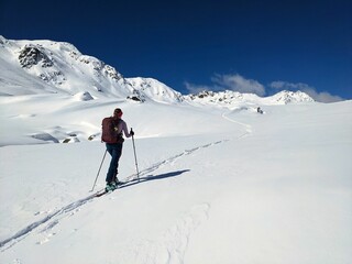 Fototapeta na wymiar Ski tourers make a lonely track through the deep snow in the mountains above Davos. Ski mountaineering in the Swiss Alps. Skitouring, ski tour, skitour, skimo. High quality photo