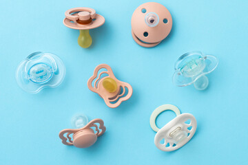 Pacifiers on blue background, newborn concept, top view of soothers, flat lay