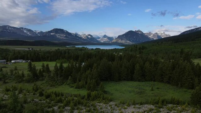 2022 - Excellent aerial footage approaching St. Mary Lake at Glacier National Park, surrounded by snow-capped mountains.