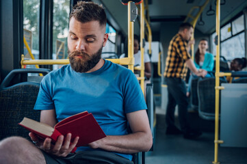 Man reading a book while riding in a bus