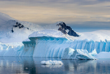 Impressive iceberg with blue ice and beautiful reflection on water in Antarctica, scenic landscape...