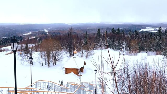 View of the chapel near the Belogorsky St. Nicholas Orthodox Missionary Monastery. Winter forest. The temple on the hill in winter. Russia, Perm Krai, Belaya Gora. 4K