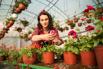 Young woman checking the quality of the plants in a greenhouse