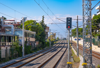 Railway tracks in the city on blue sky background. Train station, traffic light shows red signal on...