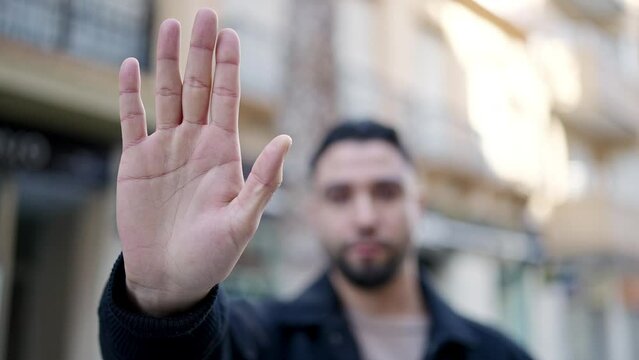 Young arab man doing stop gesture with hand at street