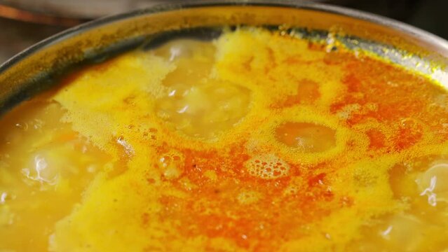 Boiling lentil soup close up. Cooking process red lentil soup. Traditional lebanese or arabic lentil and vegetable spicy soup. Static shot