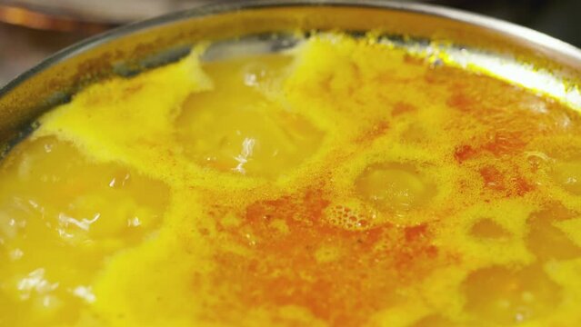 Boiling lentil soup close up. Cooking process red lentil soup. Traditional lebanese or arabic lentil and vegetable spicy soup. Static shot