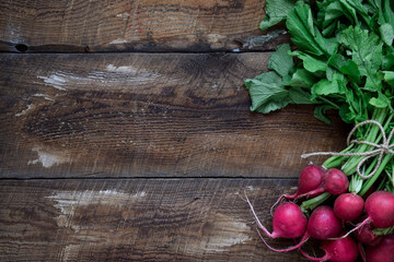 Fototapeta na wymiar A bunch of fresh red radishes on top of rustic wooden table