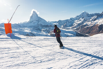 Young man snowboarding in Zermatt ski resort right next to the famous Matterhorn peak. Beautiful...