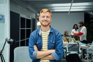 Young red-haired programmer or businessman in a modern office looking camera and smiles....