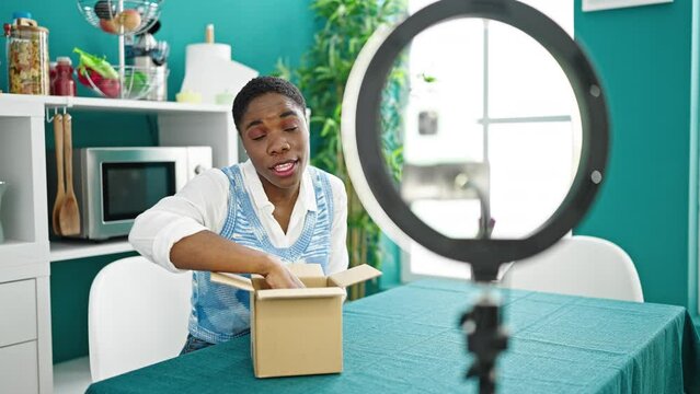 African american woman recording online tutorial for social networks unpacking professional camera at dinning room