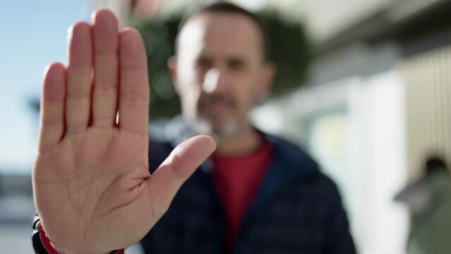 Middle age man doing stop gesture with hand at street