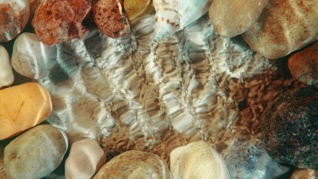 Top down view seabed background, sea floor beach sand ripple of water waves reflection, shells and stones. Yellow sandy bottom surface summer. Underwater seafloor close-up. Place for title or logo