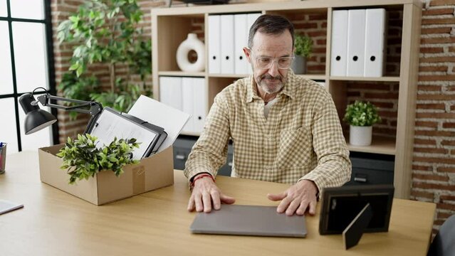 Middle age man business worker dismissed picking things up on cardboard box at office