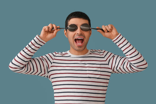 Young man with tablespoons on color background
