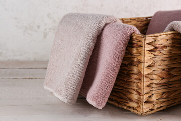 Wicker basket with soft towels on wooden table