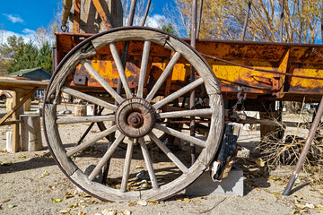 Fototapeta na wymiar An antique wagon wheel with wooden spokes on a rusty wagon