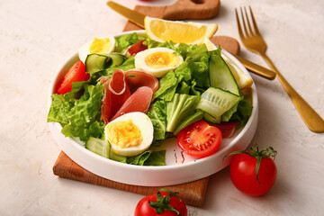 Plate of delicious salad with boiled eggs and jamon on white grunge background