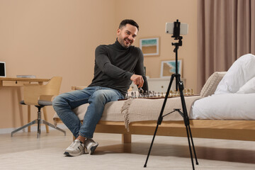 Fototapeta premium Teacher near chessboard conducting online lesson at home. Time for hobby