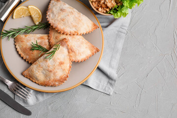 Plate with baked meat empanadas and rosemary on grunge background