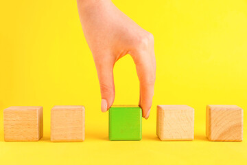 Woman with wooden cubes on yellow background