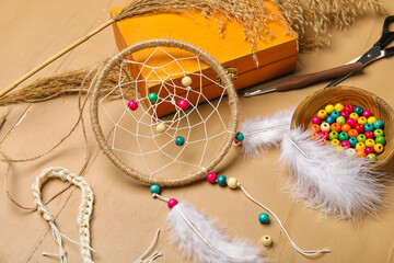 Materials for making dream catcher on beige wooden background, closeup