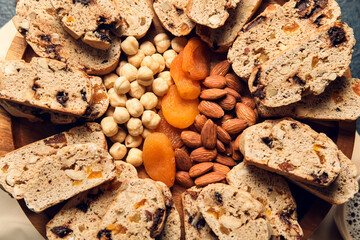 Board with biscotti cookies, nuts and dried apricots, closeup