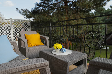 Colorful pillows and yellow chrysanthemum flowers on rattan garden furniture outdoors