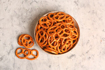 Bowl of tasty pretzels on light background
