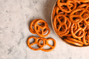 Bowl of tasty pretzels on light background, closeup