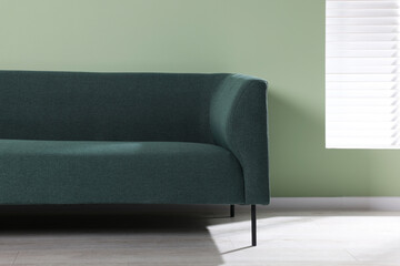 Comfortable sofa near light green wall indoors