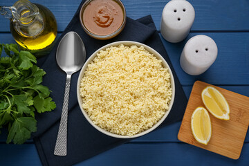 Tasty couscous and ingredients on blue wooden table, flat lay