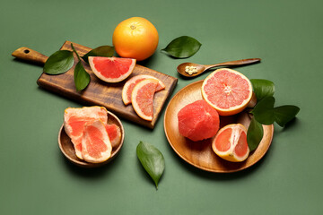 Composition with ripe grapefruits and plant leaves on green background