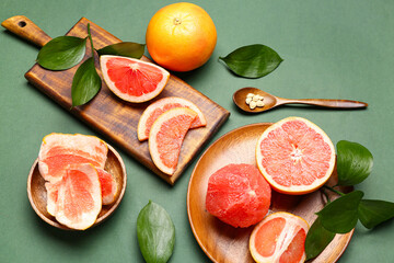 Composition with ripe grapefruits and plant leaves on green background