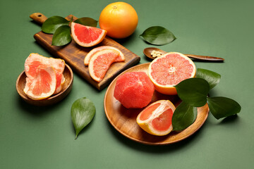 Composition with ripe grapefruits and plant leaves on green background