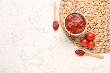 Composition with wicker mat, spoons and bowl of tasty tomato paste on white grunge background