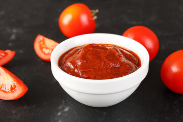 Bowl of tasty tomato paste on black grunge background