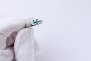 Jeweler holding topaz ring on white background, closeup. Space for text