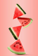 Juicy watermelon slices falling on light coral background