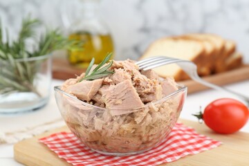 Bowl with canned tuna and rosemary on white table, closeup