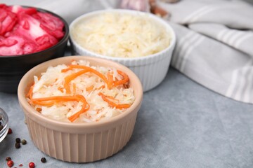 Delicious sauerkraut prepared according to different recipes on light gray table, closeup
