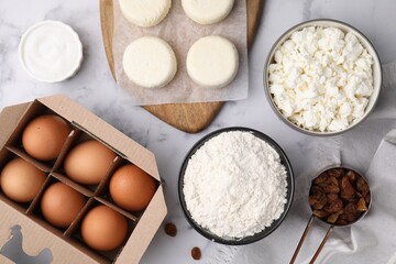 Uncooked cottage cheese pancakes and different ingredients on white marble table, flat lay