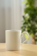 White mug on wooden table indoors. Mockup for design